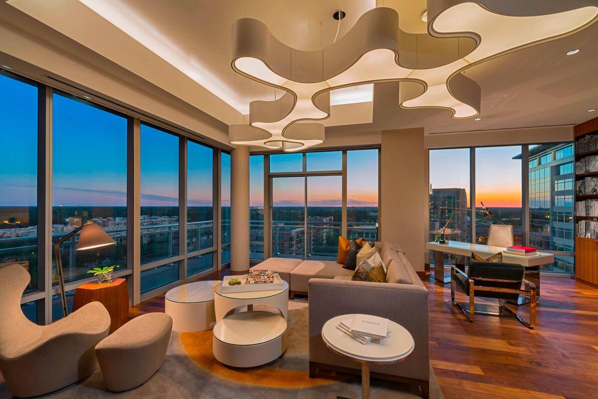 Una sala de estar moderna con vistas a la ciudad, amplios ventanales y muebles contemporáneos.