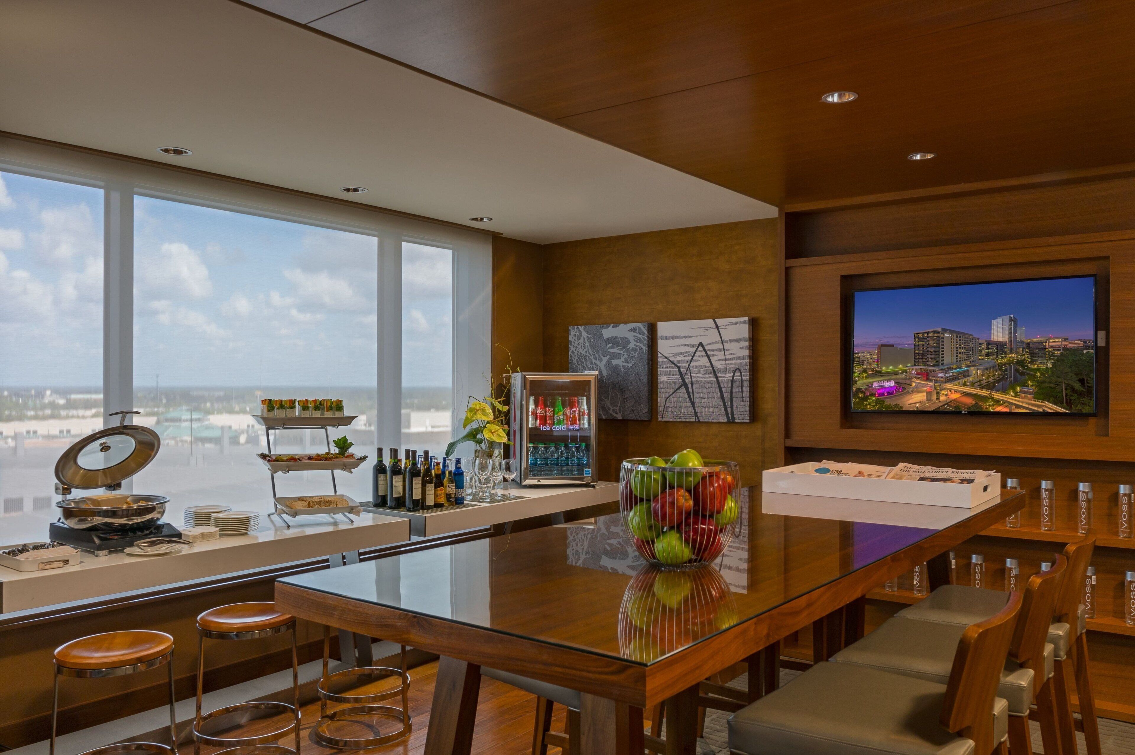 A modern bar area with a glass table, stools, and a cityscape view.