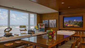 A modern bar area with a glass table, stools, and a cityscape view.