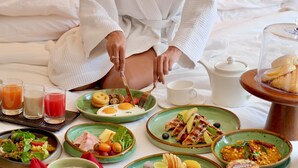 Un desayuno con diversos platos sobre una mesa, incluyendo huevos, tocino y frutas.
