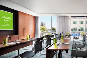 Meet in style with a spacious conference room featuring a long table, comfortable chairs, and a large screen display.