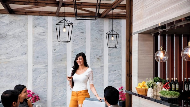 Un comedor con pared de mármol, lámparas colgantes y una zona de bar con botellas y frutas.
