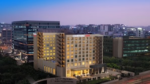 Un hotel de varios pisos con patio, arquitectura moderna y vista del paisaje urbano circundante.