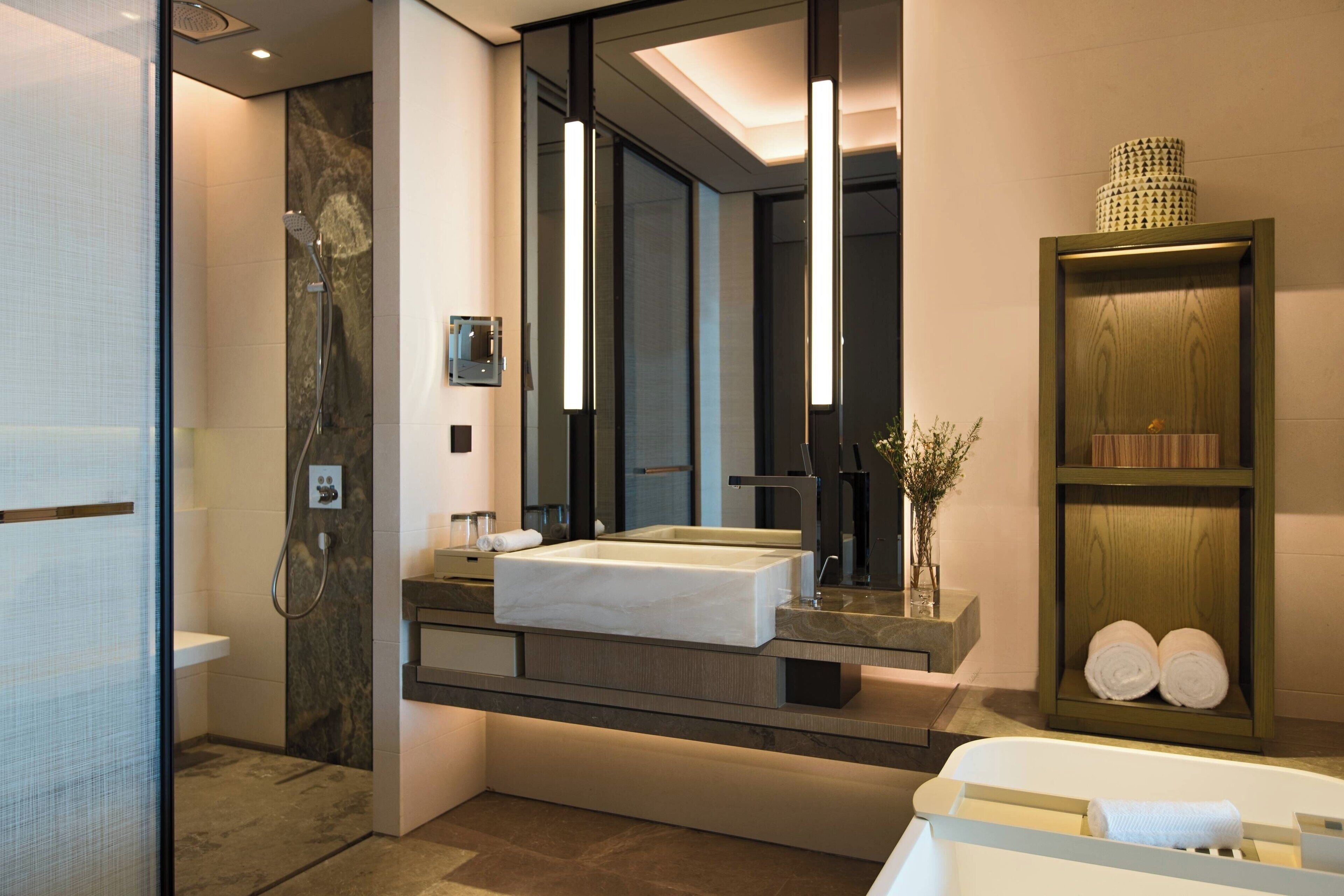 A modern bathroom with a large mirror, a rectangular sink, a shower, and a bathtub.