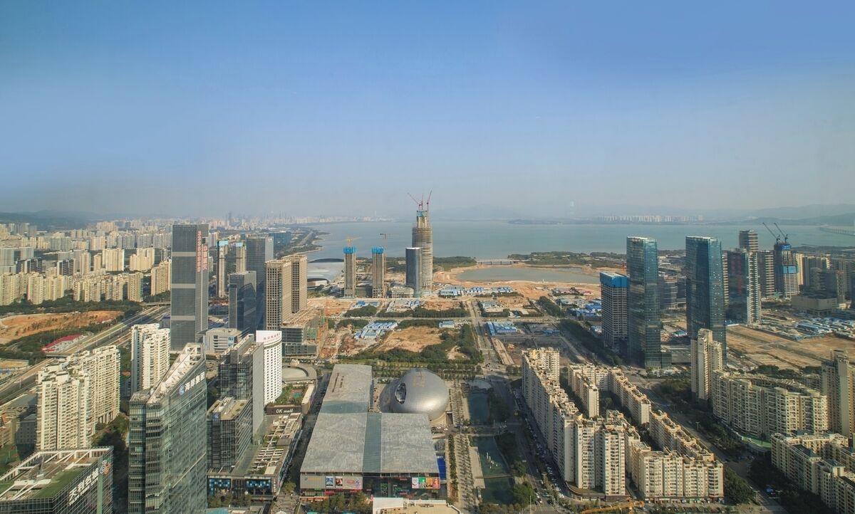 A high-rise urban area with modern buildings, a large spherical structure, and a waterfront.
