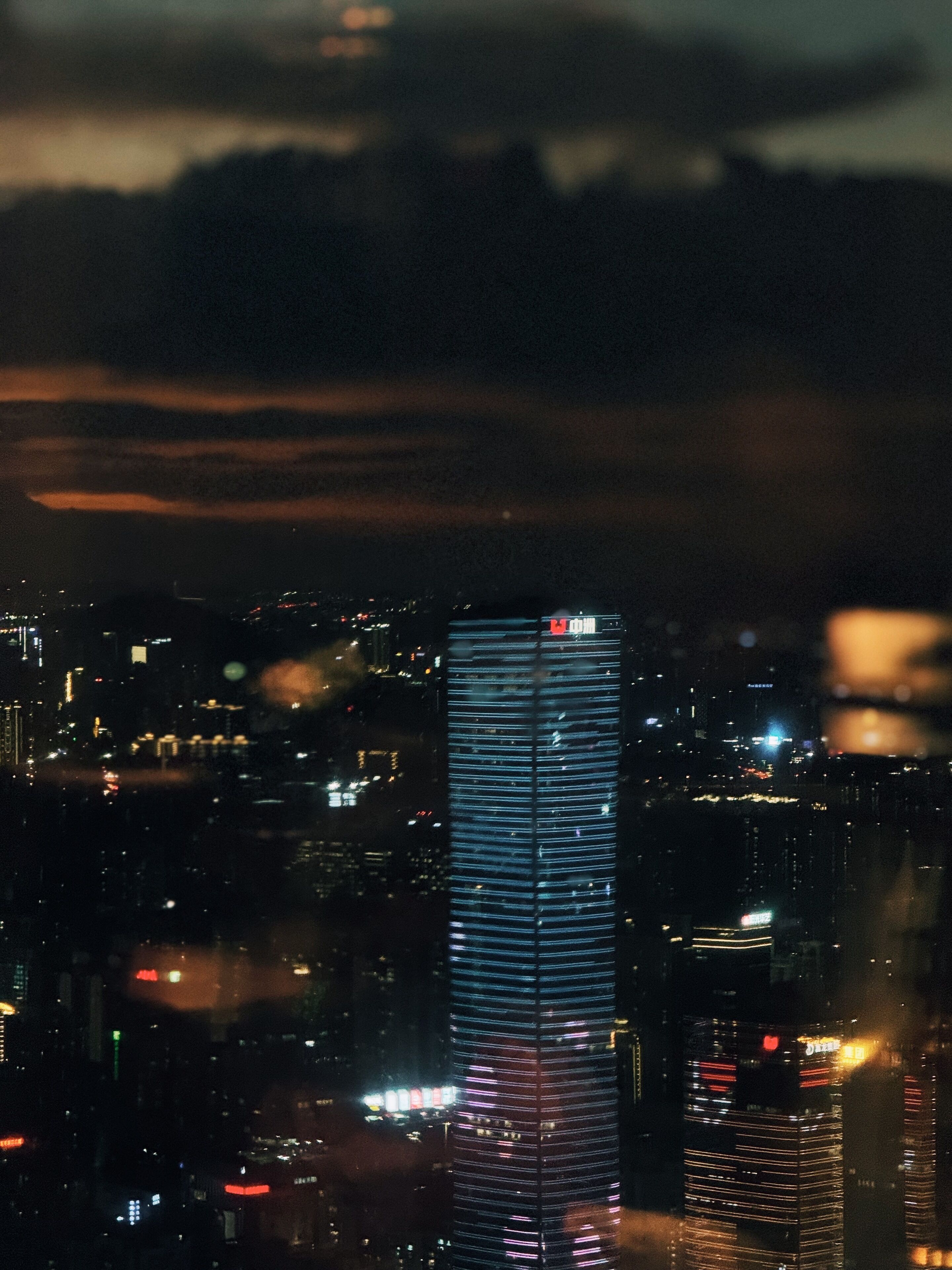 Un paisaje urbano nocturno con un rascacielos destacado, con líneas horizontales y ventanas iluminadas.