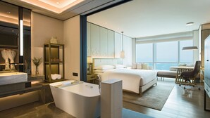 A modern hotel room with a large bed, a sitting area, a desk, a bathtub, and a view of the city. - Shenzhen Marriott Hotel Nanshan (Shenzhen)