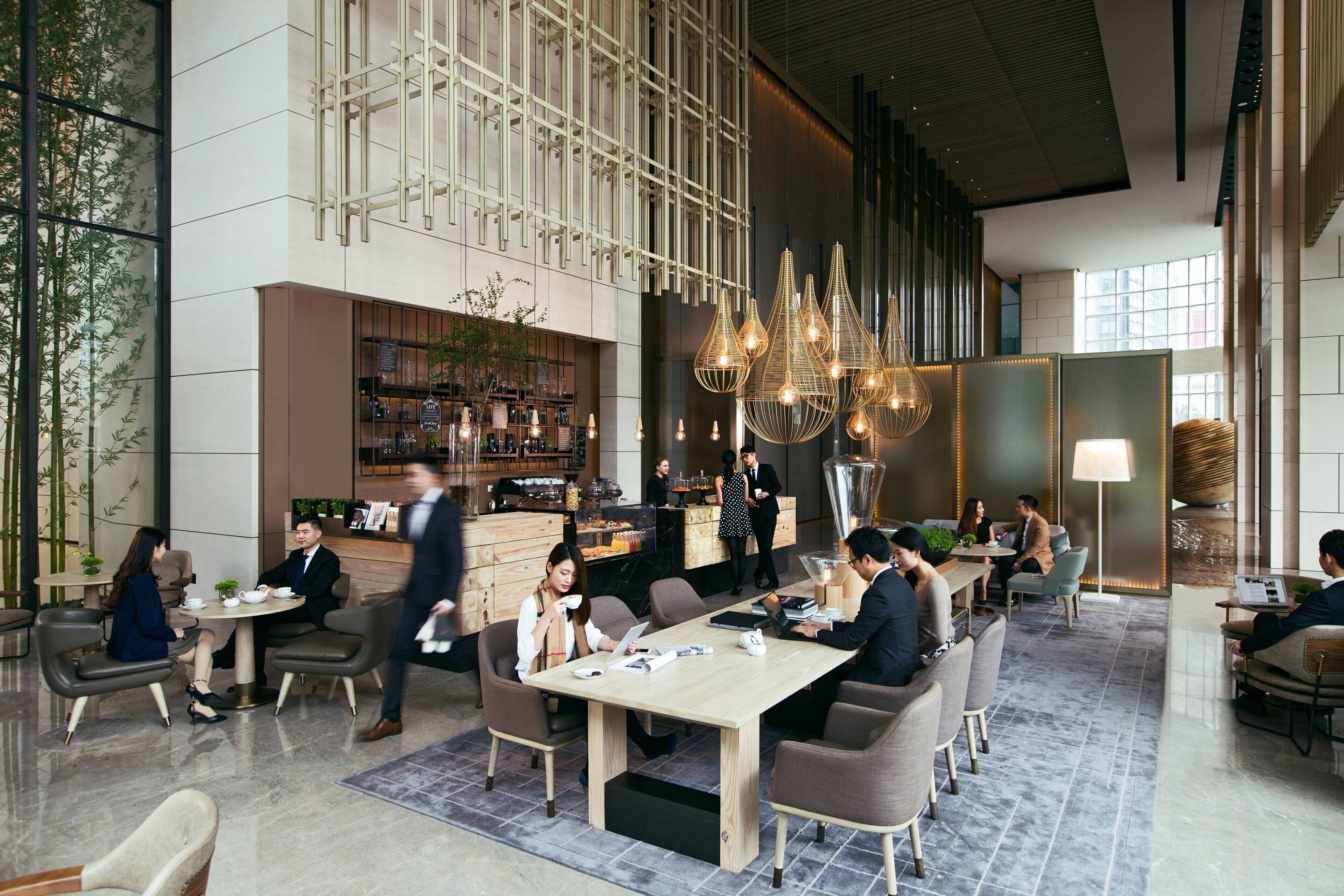 Eine moderne Hotellobby mit großzügiger Sitzecke, einer Bar und einem imposanten Kronleuchter.
