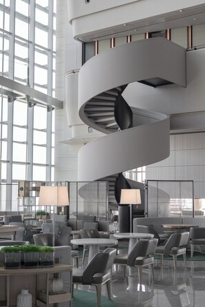 Relax in style with a spacious living area featuring a spiral staircase, comfortable seating, and large windows.