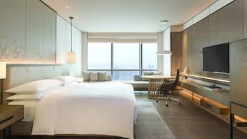 Une chambre d’hôtel moderne dotée d’un grand lit, d’un bureau, d’une chaise, d’une télévision et offrant une vue sur la ville.