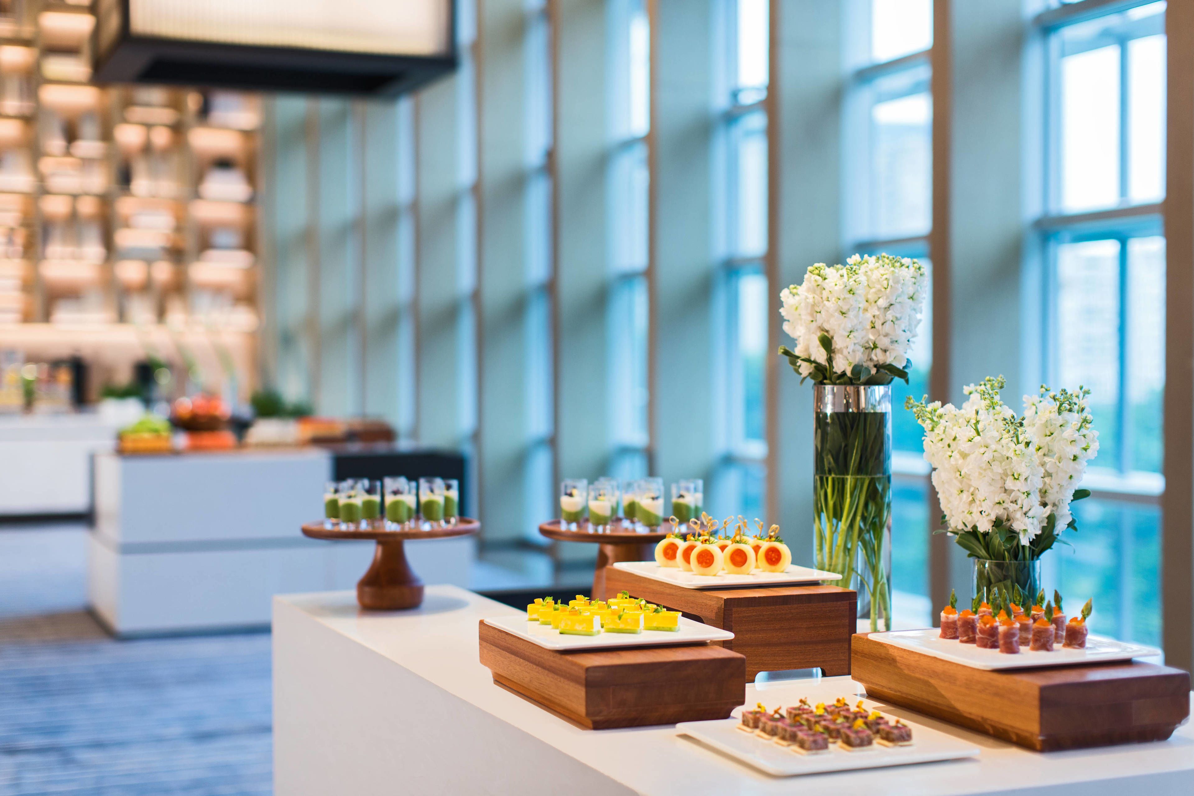 A buffet table with various food items and a vase of white flowers.