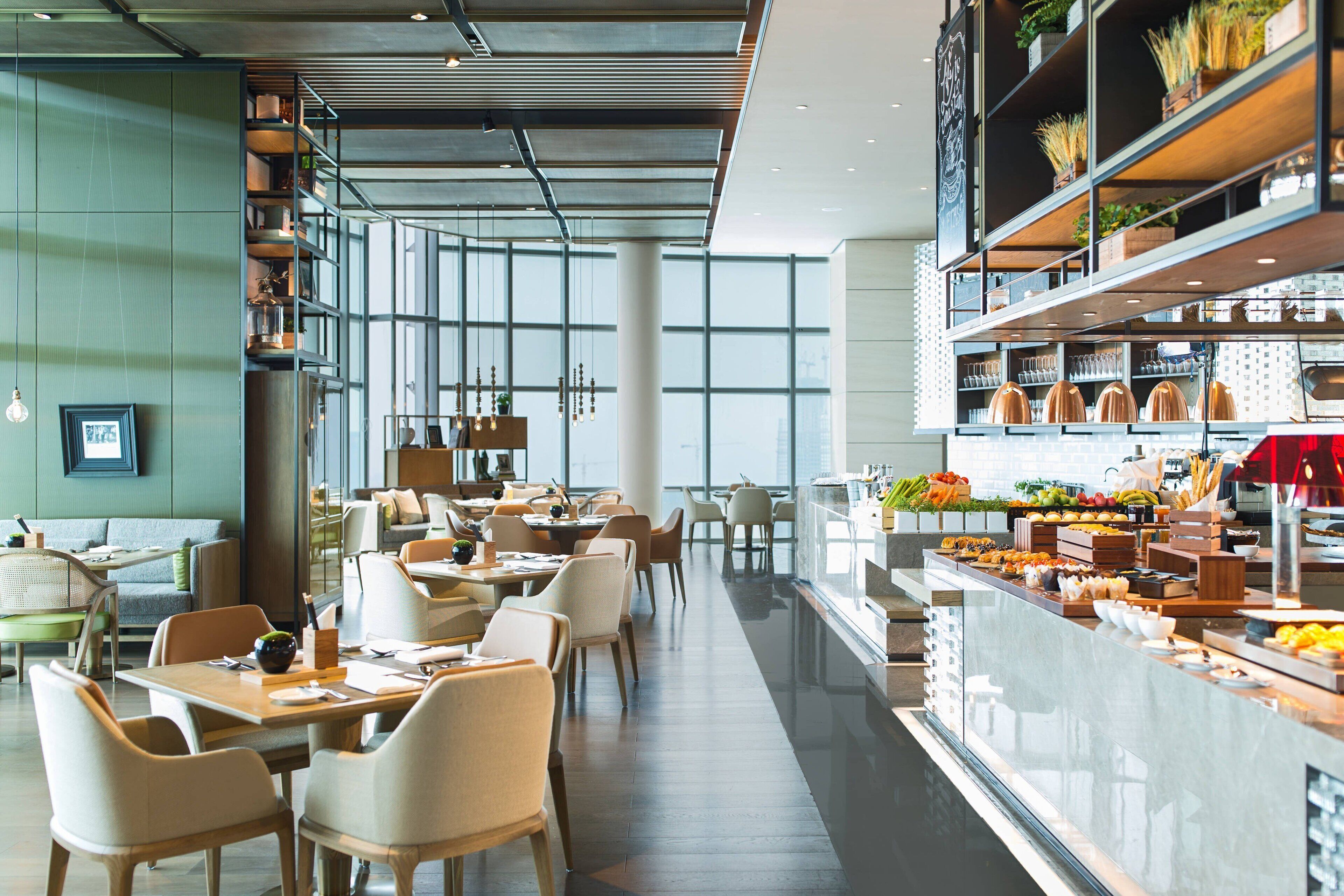 Un restaurante moderno con una barra larga, zona de estar y una variedad de alimentos a la vista.