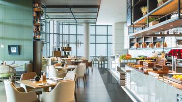 A modern restaurant with a long counter, seating area, and a variety of food items displayed.