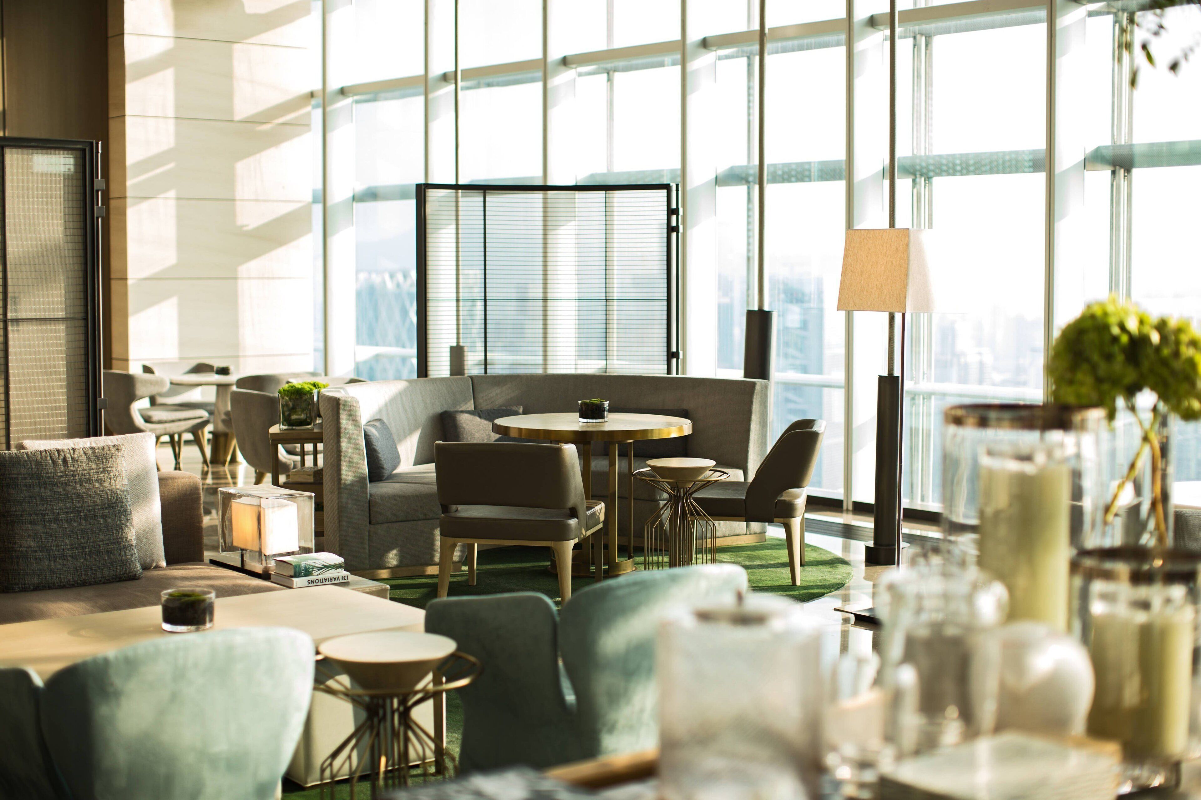 A modern hotel lobby with a seating area, large windows, and a view of the city.
