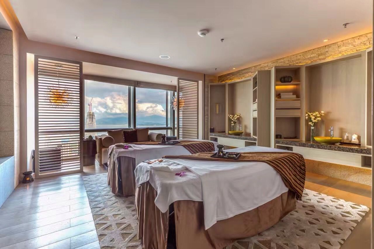 A spa room with massage tables, a reception area, and a view of the sea.