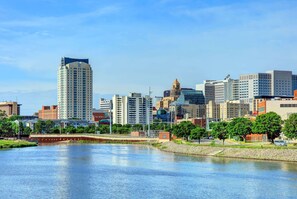 A cityscape with a river, modern buildings, and a bridge. - Broadway Plaza, Trademark Collection by Wyndham (Rochester)