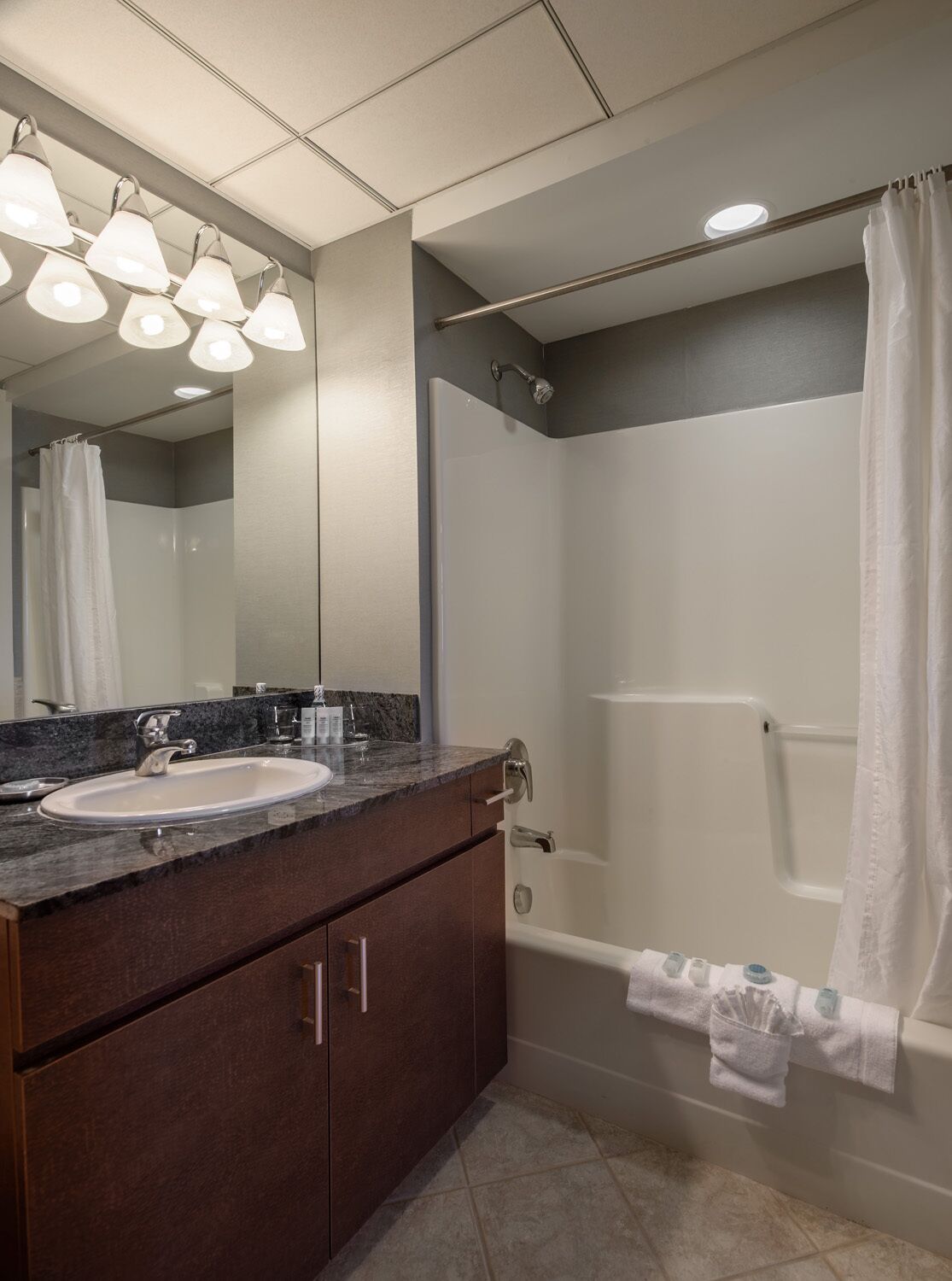 Un baño moderno con lavamanos, espejo y ducha.