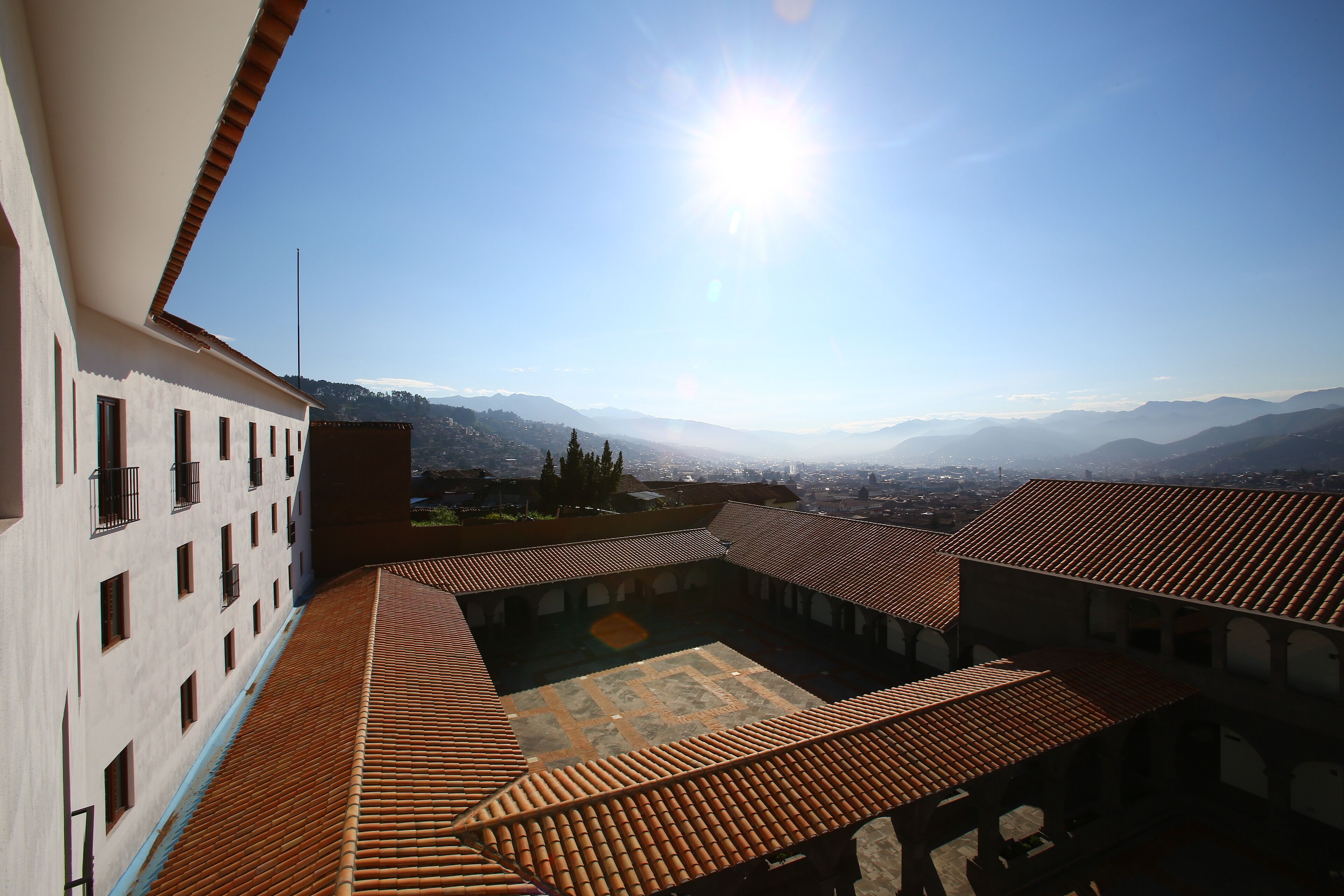 A courtyard with tiled roofs and a view of distant mountains.
