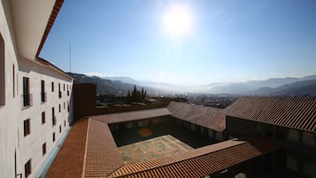 Une cour avec des toits en tuiles et une vue sur des montagnes lointaines.