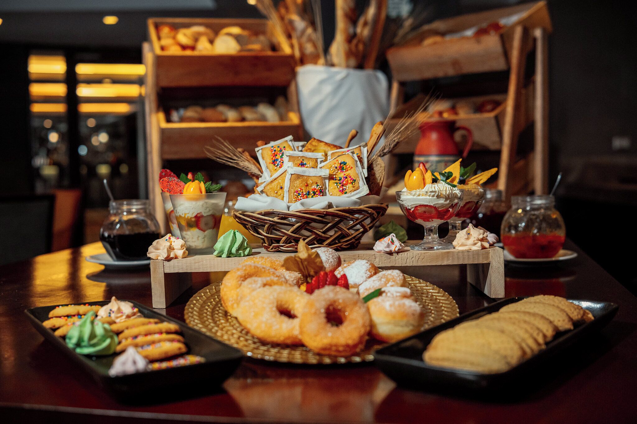 A table with various pastries and desserts, including donuts, cookies, and a cake with a house decoration.