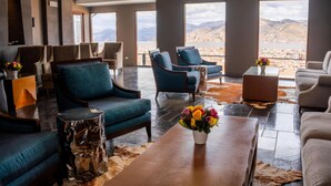 A spacious lounge with multiple seating areas, large windows offering mountain views, and a central coffee table with a floral arrangement. - Hilton Garden Inn Cusco (Cusco)