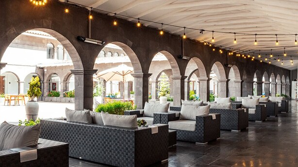A covered outdoor seating area with modern furniture and arches. - Hilton Garden Inn Cusco (Cusco)