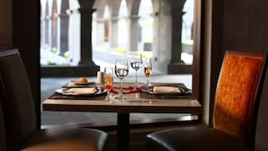 A dining table set with glasses and plates, with a view of an outdoor courtyard through an arched window. - Hilton Garden Inn Cusco (Cusco)