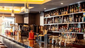 A bar area with a polished marble countertop, shelves stocked with various liquor bottles, and a seating area with bar stools. - Hilton Garden Inn Cusco (Cusco)