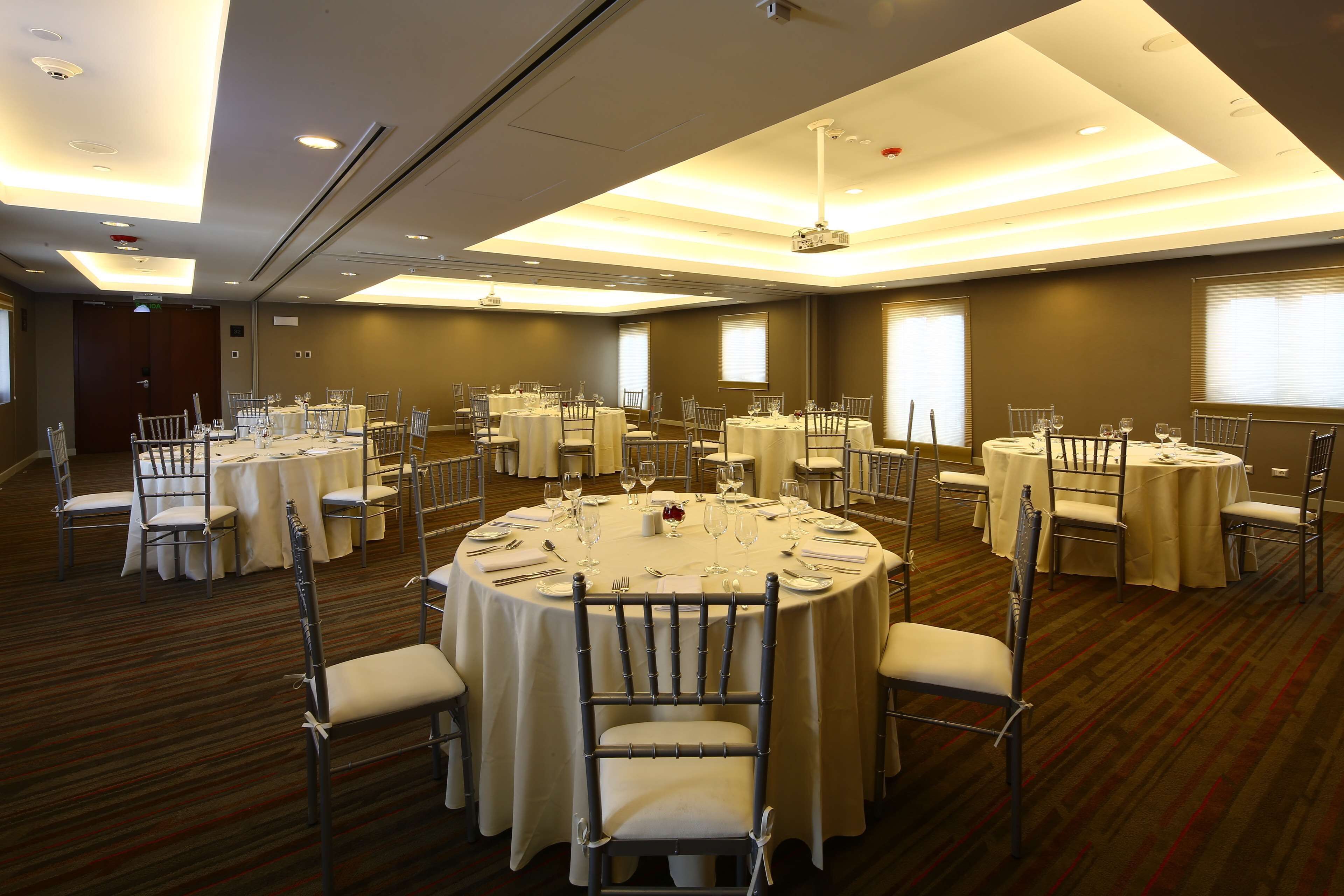 A conference room with multiple round tables, each set with chairs, glasses, and cutlery.