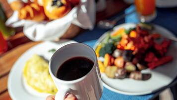 A breakfast table with a cup of coffee, a plate of eggs, and a basket of pastries.