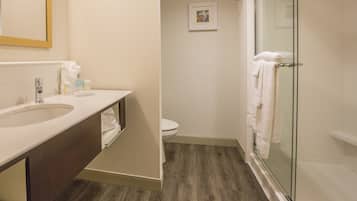 A bathroom with a sink, toilet, and glass shower enclosure.