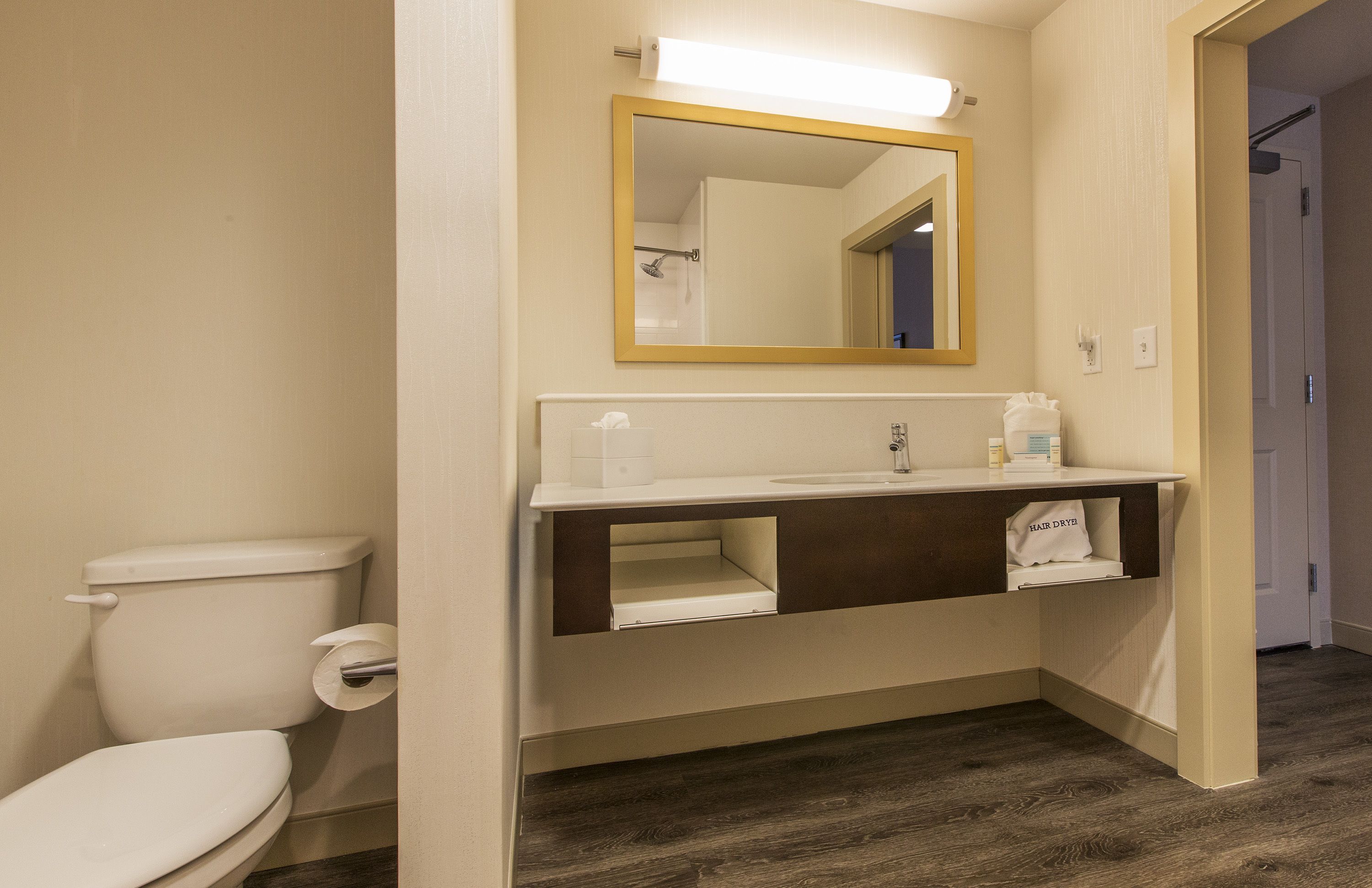 A bathroom with a toilet, sink, mirror, and towel rack.