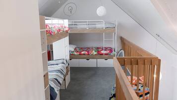 Cozy bunk bed room with a sloped ceiling and minimalist design, featuring a single light fixture and two bunk beds with metal railings and wooden headboards.