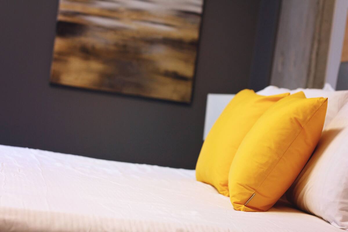 A bed with two yellow pillows and a white bedspread.