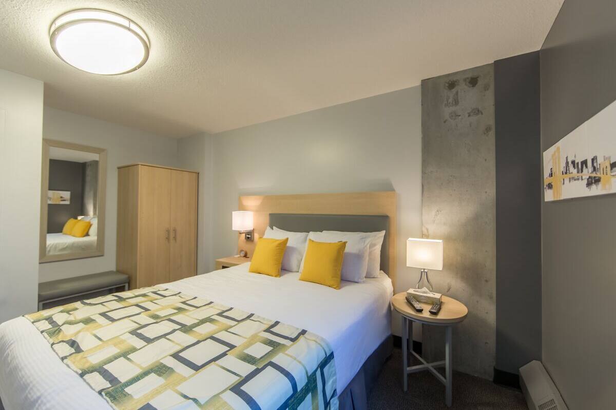 A hotel room with a large bed, two bedside tables, a wardrobe, and a mirror.