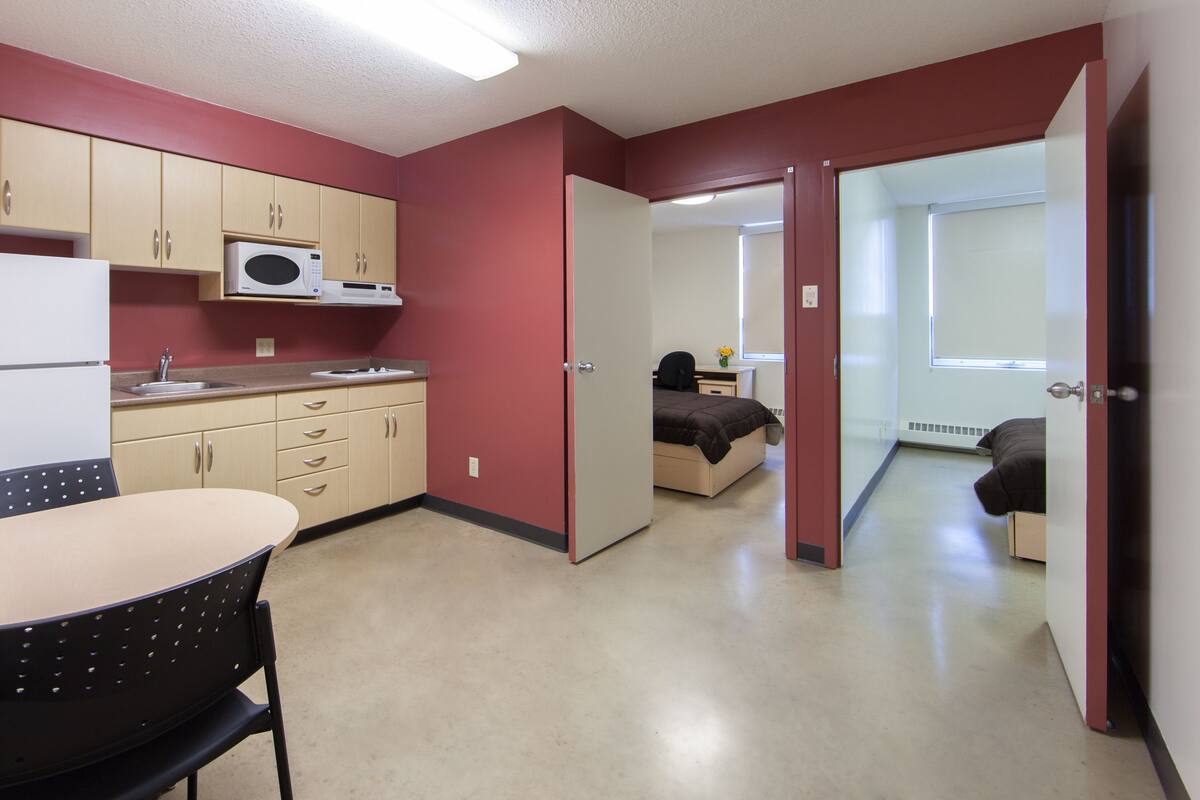 A compact room with a kitchenette, a bed, and a small desk.
