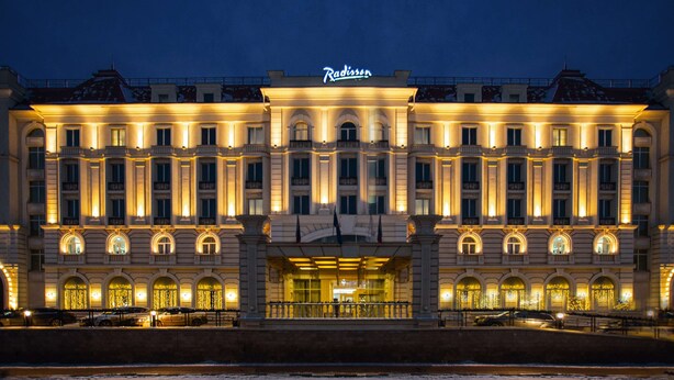 A grand hotel with a classic European architectural style, featuring symmetrical facades, arched windows, and a central entrance.