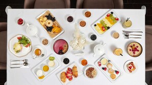 A table set with various breakfast items including pastries, fruits, and beverages, arranged on a white tablecloth.