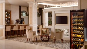 A hotel lobby with a bar area, seating, a television, and a wine rack.