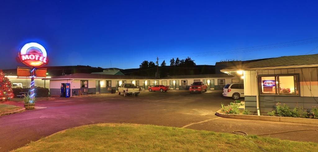 A motel with multiple rooms, a neon sign, and a parking lot.