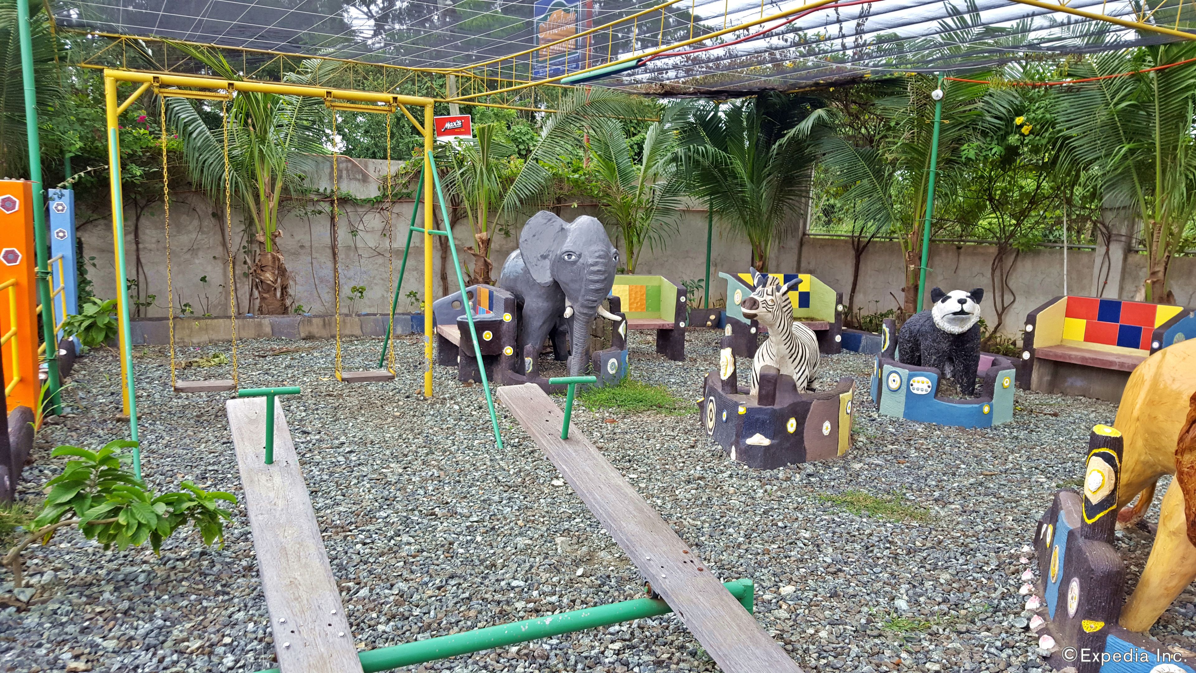 A playground with swings, a climbing structure, and animal sculptures.