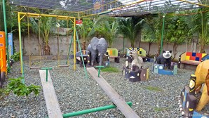 Un parque infantil con columpios, una estructura para escalar y esculturas de animales.