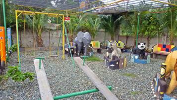 A playground with swings, a climbing structure, and animal sculptures.