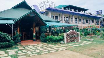 A building with a green roof and a sign that reads "Nicholle Pension".