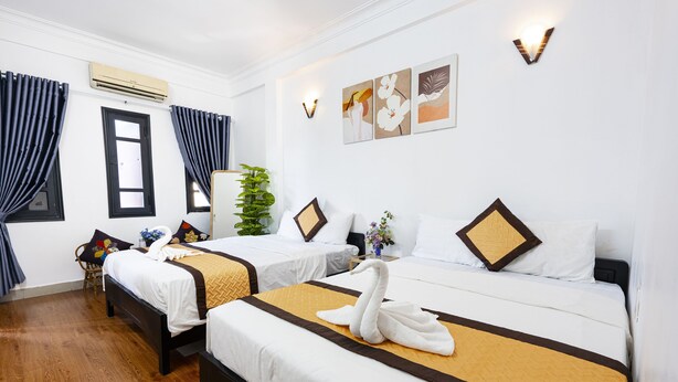 Ein Hotelzimmer mit zwei Betten, einer Zimmerpflanze und Bildern an der Wand.