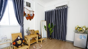 Ein Zimmer mit einer Holzsofa, einem kleinen Tisch, einem Spiegel, einer Zimmerpflanze und einem Kühlschrank.