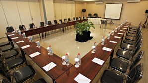 A conference room with a long table, chairs, water bottles, and a projector screen. - Nite & Day Surabaya - Gunungsari (Surabaya)