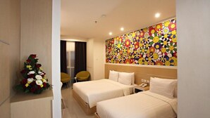 A hotel room with two beds, a floral arrangement, a colorful wall mural, and a modern design. - Nite & Day Surabaya - Gunungsari (Surabaya)