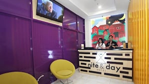 A reception desk with a 'nite & day hotel' sign, two staff members, and a television screen. - Nite & Day Surabaya - Gunungsari (Surabaya)