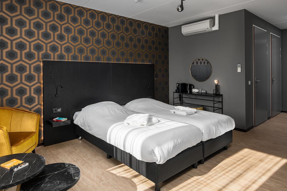 Une chambre d’hôtel moderne avec un grand lit, une table de chevet avec une lampe, une chaise et une armoire.